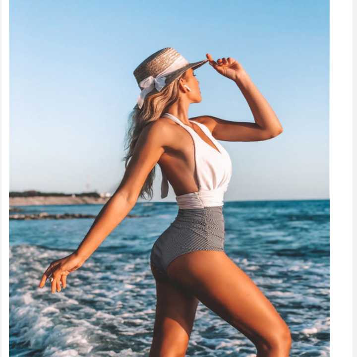 Frau im weiΓen Badeanzug mit Strohhut am Strand, Sommermode, Meereshintergrund.